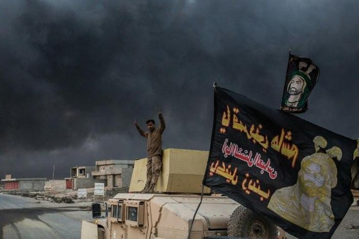 A member of the Iraqi forces stands on an armoured vehicle as smoke billows from the Qayyarah area, some 60 kilometres (35 miles) south of Mosul