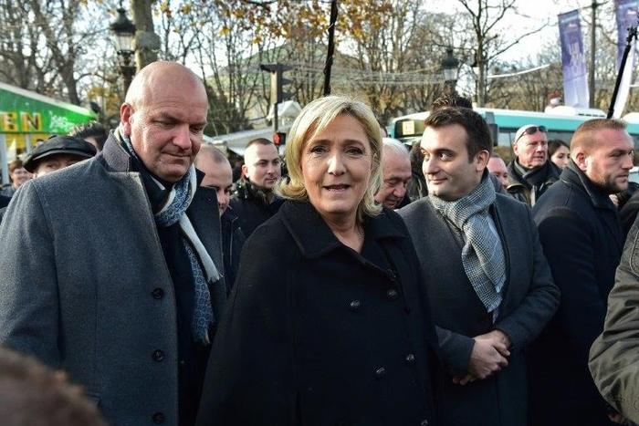 French far-right Front National party president,and candidate for France's 2017 presidential election, Marine Le Pen (C) walks along with FN vice-president Florian Philippot (R) during a visit of a Christmas market in Paris on December 8, 2016