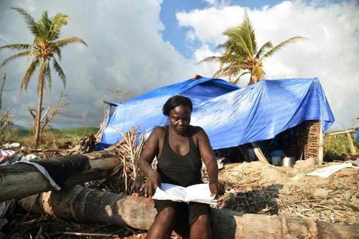 A woman sits close to her house damaged by Hurricane Matthew in the village of Labeyi, in southwestern Haiti, on November 3, 2016