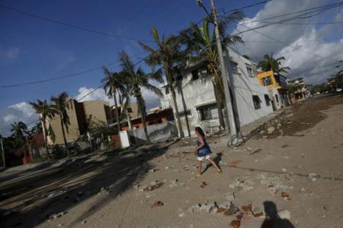 A woman walks along a street damaged by the heavy rains after the passing of Hurricane Patricia in Barra de Navidad, Mexico October 24, 2015.