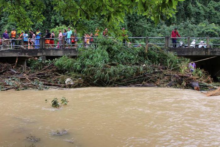 Onlookers and rescue workers stand on a bridge in a flooded area in Sichon District, Nakhon Si Thammarat province, Thailand December 4, 2016.