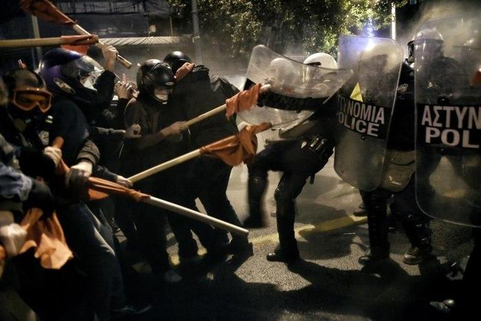 Demonstrators holding red flags clash with Greek riot police during a protest against the visit of the US president in Athens on November 15, 2016