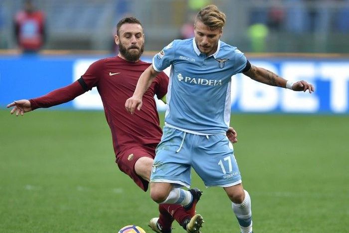 Roma's midfielder from Italy Daniele De Rossi (L) tackles Lazio's forward from Italy Ciro Immobile during the Italian Serie A football match SS Lazio vs AS Roma on December 4, 2016