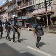 Nepalese police in riot gear walk past shuttered shops in Kathmandu.