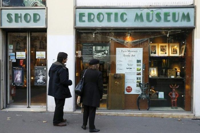 Two people stand in front of the the Erotic Museum of Paris on November 2, 2016 prior to the auction sale of the collection on November 6 and the closure of the museum