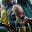 A woman holds her child while waiting in a queue at one of the UNICEF nutrition clinics in Muna informal settlement, in northeastern Nigeria in June 2016