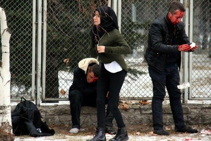 Injured people wait for an ambulance following an explosion in Kayseri, central Turkey, which killed 14 soldiers and wounded dozens of others