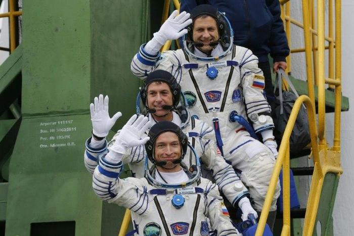 Russian cosmonauts Sergei Ryzhikov (bottom) and Andrei Borisenko (top) and US astronaut Shane Kimbrough wave as they board the Soyuz MS-02 spacecraft at the Russian-leased Baikonur cosmodrome on October 19, 2016