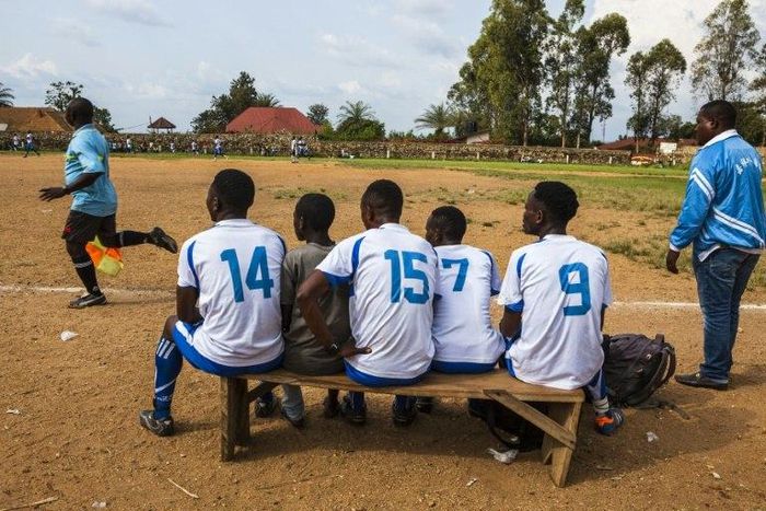 Local football players follow a match from the bench in Beni, DR Congo