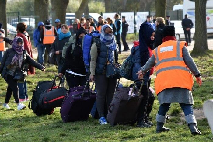 Migrants carry their luggages as they walk to climb into a bus after leaving the "Jules Ferry" reception centre, next to the recently demolished "Jungle" migrant camp after a massive operation to clear the settlement, on November 3, 2016, in Calais