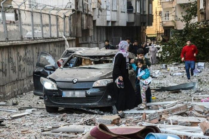 Women and children walk away from a damaged building at the site of an explosion in Diyarbakir, southeast Turkey on November 4, 2016