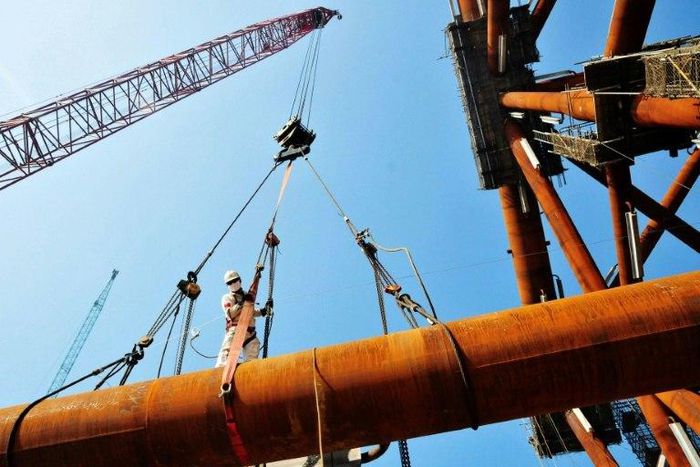 A worker stands on pipes at an offshore oil engineering company in Qingdao, in China's eastern Shandong province