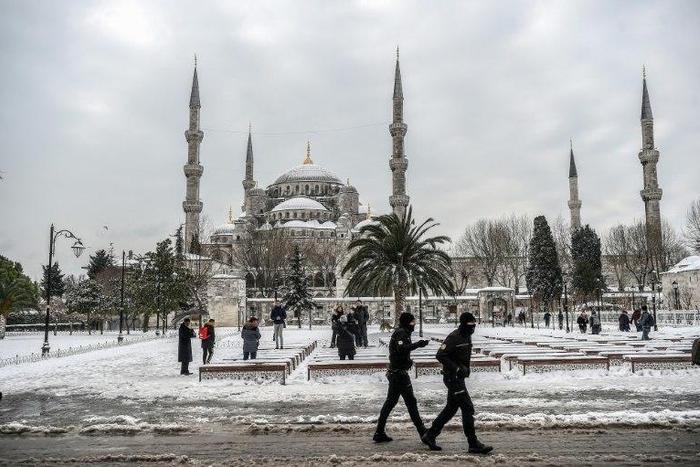 Turkish police officers patrol around the Blue mosque (Sultan Ahmet) during snowfall in Istanbul on January 8, 2017