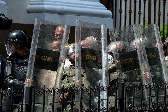 National Guard members protect opposition lawmakers under attack by supporters of President Nicolas Maduro's government while trying to enter to the National Assembly