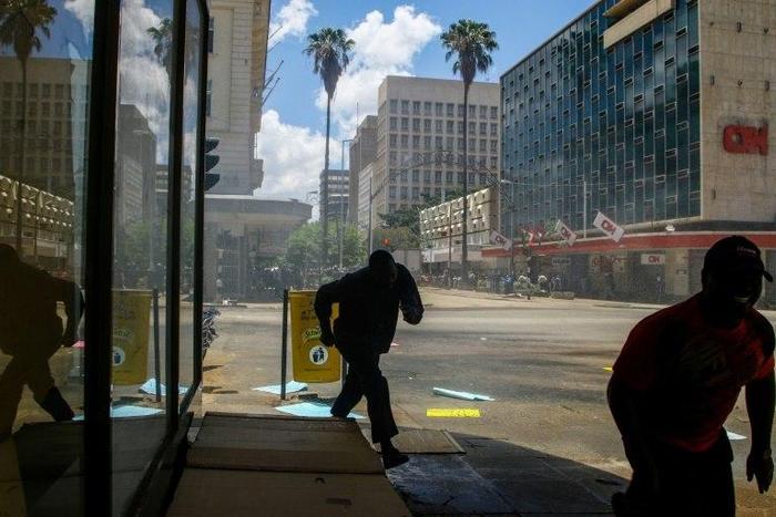 People run away from Zimbabwe police officers using a water canon during a demonstration by opposition parties against the introduction of bond notes as a currency in Harare, on November 30, 2016