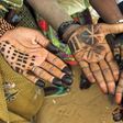 Children decorate their hands with henna.