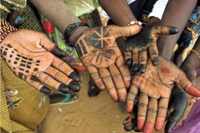 Children decorate their hands with henna.