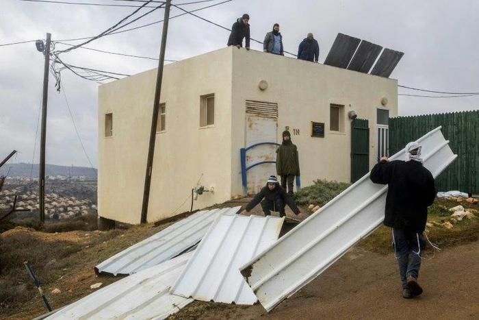 Israeli settlers block the entrance to the the settlement outpost of Amona, in the Israeli-occupied West Bank