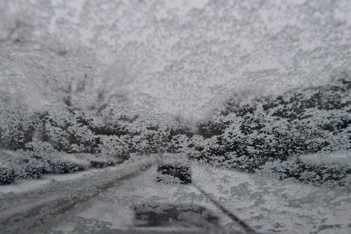 View of a park shot through a windshield covered in snow, in Berlin on January 7, 2017