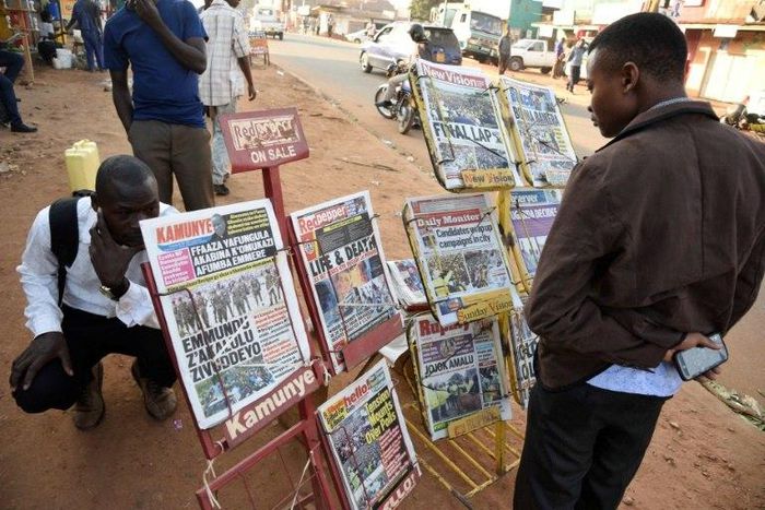 A man reads newspaper headlines at a Kampala news-stand