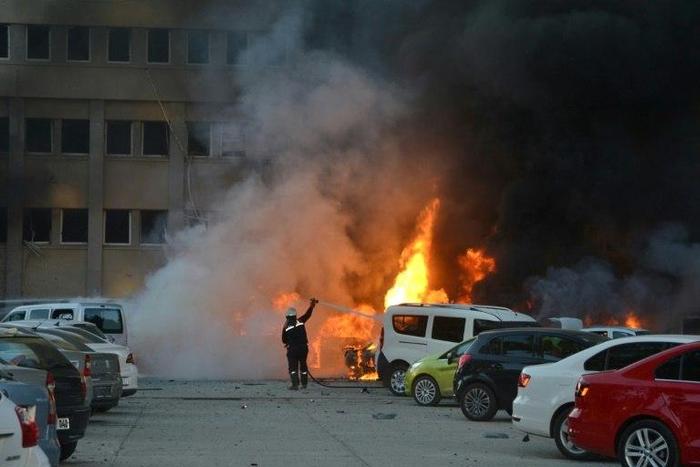 A firemen extinguishes flames from a burning car after an explosion in Adana, southern Turkey on November 24, 2016