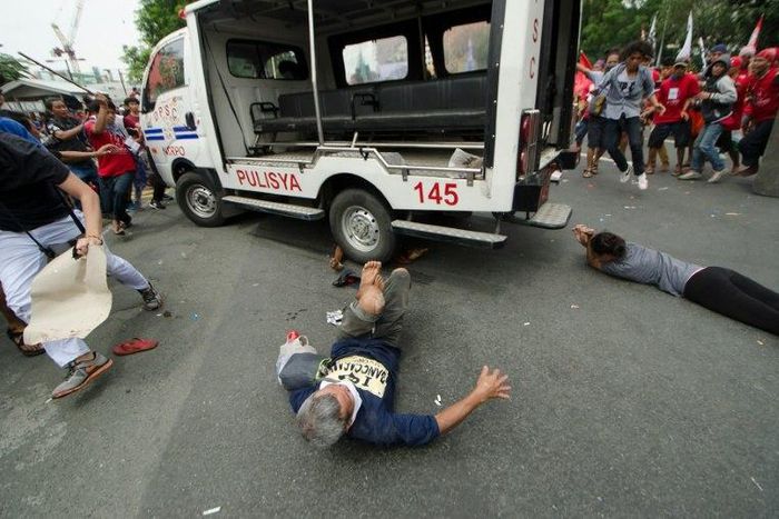 Protesters lie on the ground after being hit by a police van during a rally in front of the US embassy in Manila on October 19, 2016
