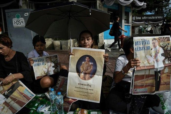 People hold newspaper images of Thailand's new King Maha Vajiralongkorn outside the Grand Palace in Bangkok