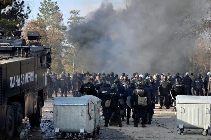 Bulgarian riot police stand near garbarge bins during clashes in the migrants reception centre in the town of Harmanli on November 24, 2016