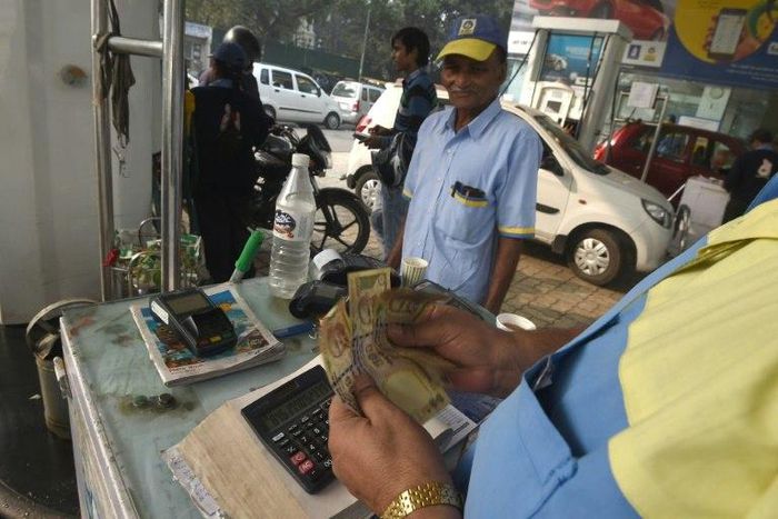 An Indian customer pays for fuel with old 500 rupee notes at a petrol station in New Delhi on the last day on which the old currency can be used to purchase fuel