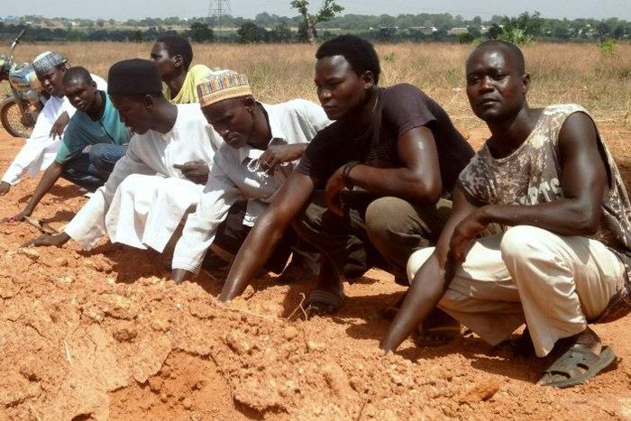 Members of the Islamic Movement of Nigeria, a Shiite group, pray at a mass grave in which 300 members of the organisation are said to be buried