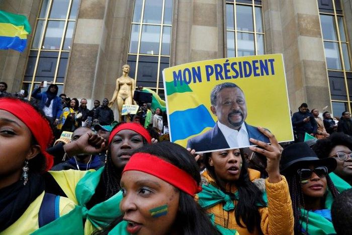 Supporters of Gabonese opposition leader Jean Ping wrapped in Gabonese flags gesture after his speech on October 29, 2016 on the Human Rights Esplanade in Paris