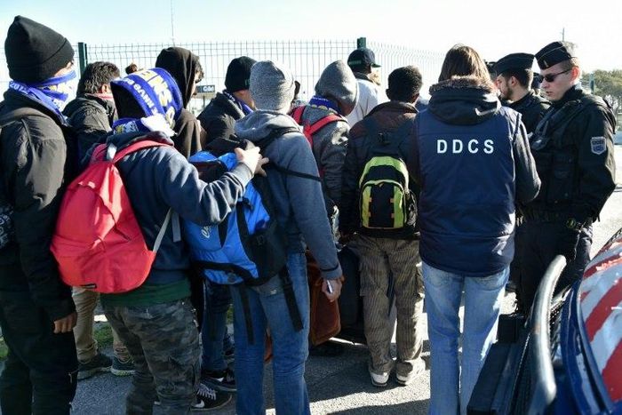 French police officers and charity workers escort young migrants to board a bus leaving for a reception centre, in Calais, on October 28, 2016