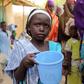 A girl drinks water as women queue for blankets and food given out by Nigerien soldiers in Damasak