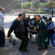 Egyptian emergency services carry a wounded victim at the site of a bomb attack next to a police checkpoint in Cairo on December 9, 2016