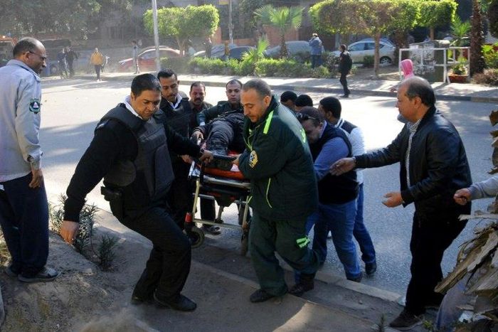 Egyptian emergency services carry a wounded victim at the site of a bomb attack next to a police checkpoint in Cairo on December 9, 2016