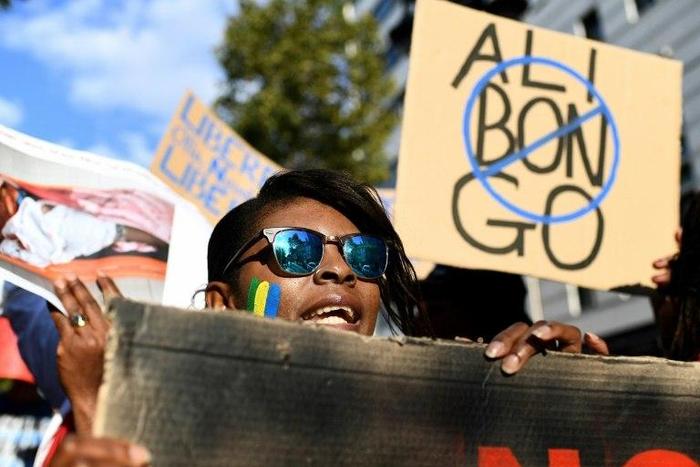 People hold a banner and photos during a demonstration of Gabonese associations in Marseille, southern France on September 24, 2016 to protest against the validation of reelection of Gabon's president Ali Bongo