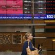 People pass a stock board showing stocks in red outside the Singapore Exchange in the central business district in Singapore August 12, 2015.