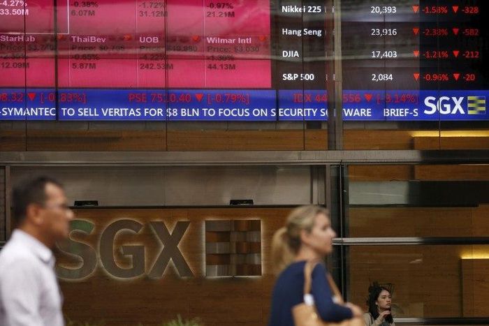People pass a stock board showing stocks in red outside the Singapore Exchange in the central business district in Singapore August 12, 2015.