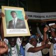 Patriotic Front General Secretary Davies Chama (L) celebrates while holding a portrait of President Edgar Chagwa Lungu after Lungu narrowly won re-election on Monday, in a vote his main rival Hakainde Hichilema rejected on claims of alleged rigging by ...