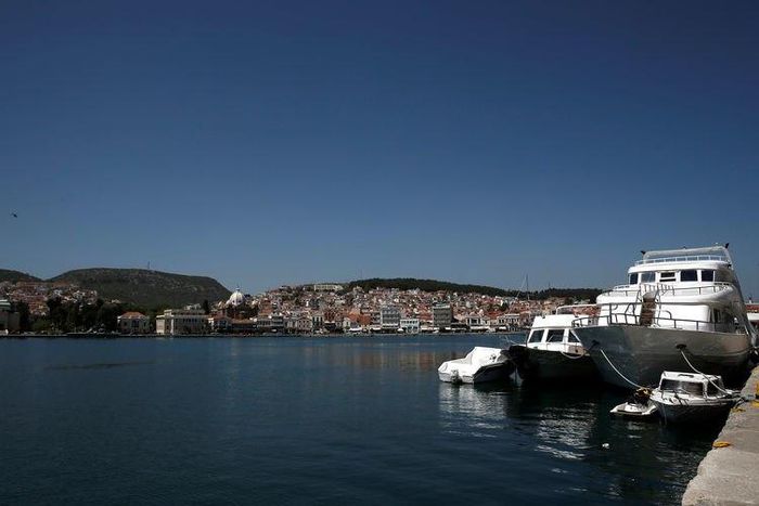 Vessels used by refugees and migrants to cross the Aegean Sea from Turkey are docked as the port city of Mytilene is seen in the background on the Greek island of Lesbos April 15, 2016. REUTERS/Alkis Konstantinidis