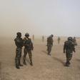 Cameroonian soldiers from the Rapid Intervention Brigade stand guard amidst dust kicked up by a helicopter in Kolofata, Cameroon, March 16, 2016.