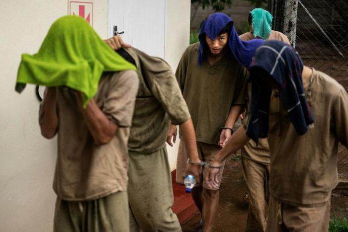 Chinese nationals cover their faces from cameras with towels as they leave the courtroom on January 3, 2019, at the Victoria Falls magistrate court where they faced charges of breaching Zimbabwe's wildlife laws for possessing rhino horn pieces