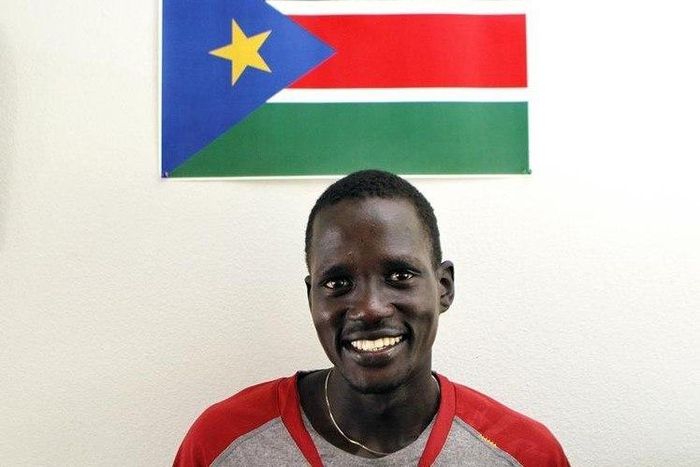 Guor Marial, 28, smiles in his apartment under a South Sudan flag in Flagstaff, Arizona July 21, 2012.