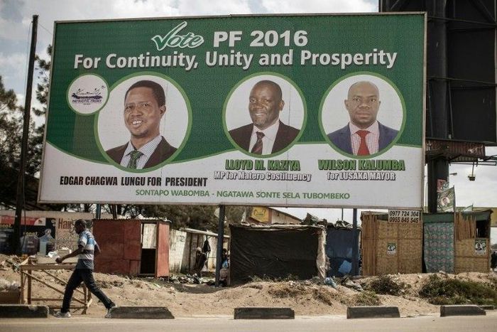 People walk by a billboard with picture of the incumbent president Edgar Lungu, of the Patriotic Front ruling Party, two days ahead of Zambian Presidential and legislative elections on August 9, 2016