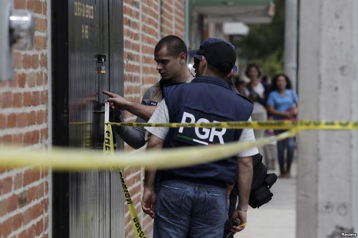 Federal agents inspect bullet impacts at a crime scene in Ocotlan, Mexico