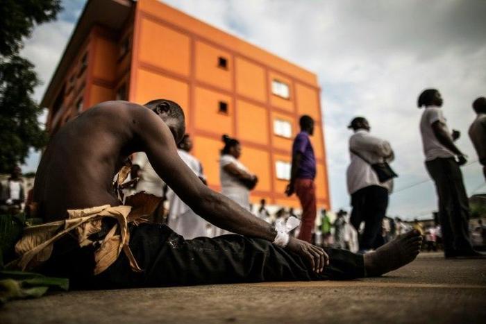A man traditionally dressed with banana leaves joins mourners paying their respects at an improvised altar for those who perished during the post electoral violence in Libreville on September 6, 2016