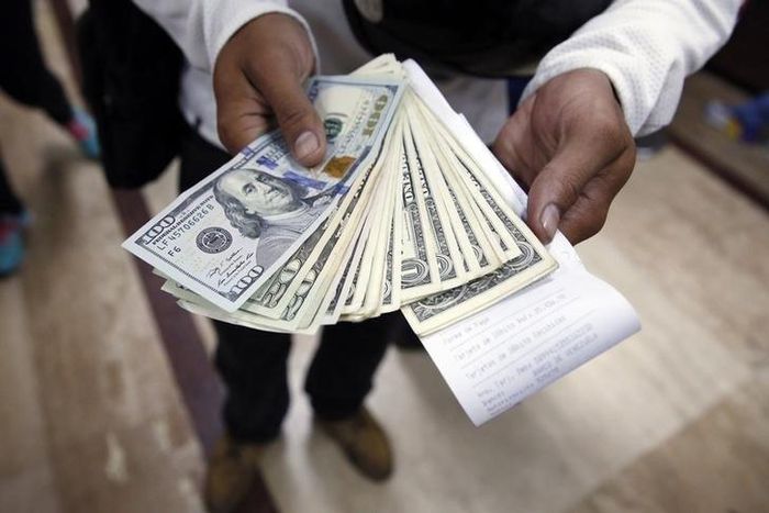 A man poses with dollars, after buying them at a money exchange in Caracas, Febreuary 24, 2015.    REUTERS/Carlos Garcia Rawlins