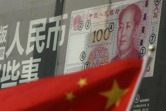 China's national flag is seen in front of a poster explaining the design of new 100 yuan banknote at a branch of a commercial bank at a business district in Beijing, China, January 21, 2016.