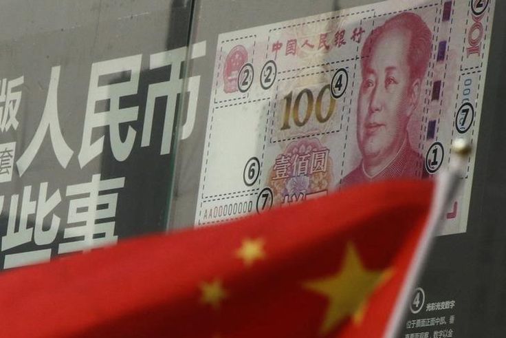 China's national flag is seen in front of a poster explaining the design of new 100 yuan banknote at a branch of a commercial bank at a business district in Beijing, China, January 21, 2016.
