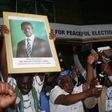 Patriotic Front General Secretary Davies Chama (L) celebrates while holding a portrait of President Edgar Chagwa Lungu after Lungu narrowly won re-election on Monday in the capital, Lusaka, Zambia, August 15, 2016.